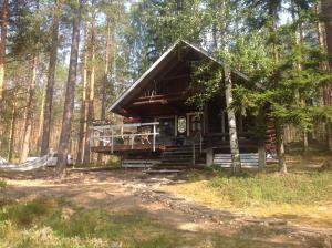 eine Blockhütte im Wald mit einer Veranda in der Unterkunft Kesämökki RUOKOLAHTI in Talkkuna