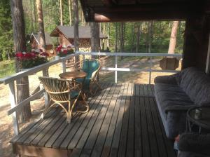 porche de madera con sofá y mesa en Kesämökki RUOKOLAHTI en Talkkuna