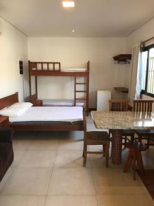 um quarto com 2 beliches e uma mesa em Suites Grande Tenorio em Ubatuba