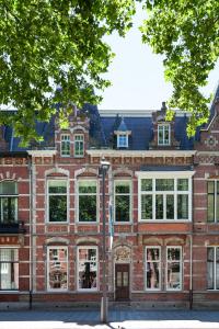 um antigo edifício de tijolos vermelhos com janelas brancas em Hotel Julien em Den Bosch
