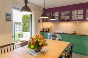 a kitchen with a table with a vase of flowers on it at Wanderlust Guesthouse in Weggis