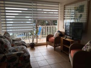sala de estar con sofás, TV y balcón en Bahia Pelicanos, Horcon departamento Mabel en Horcón