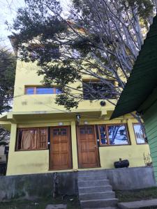 a yellow house with wooden doors and stairs at chula"s house in Ushuaia