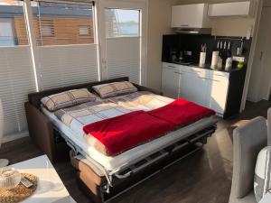a bedroom with a bed with a red blanket on it at Hausboot Harmonie in Bitterfeld