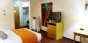 a hotel room with a bed and a television at Howard Johnson by Wyndham Fort St. John in Fort Saint John