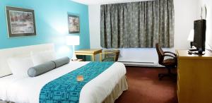 una camera d'albergo con letto, scrivania e TV di Howard Johnson by Wyndham Fort St. John a Fort St. John