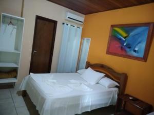 a bedroom with a white bed and a painting on the wall at Pousada Recanto Lagoa Azul in Baixio +77 photos