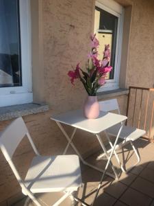 un vase de fleurs assis sur une table avec deux chaises dans l'établissement Monteur Apartment Rodenbach, à Rodenbach