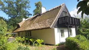 una pequeña casa blanca con techo de paja en BILLE's HUS, en Tisvildeleje