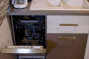 a kitchen with an open dishwasher under a counter at Carla's apartment -shuttle in Iaşi +42 photos