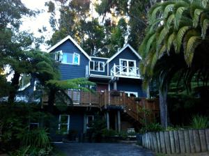 a blue house with a porch and a balcony at Titirangi Paradiso in Titirangi