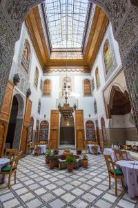 Habitación grande con mesas, sillas y techo. en Riad Fes Iline, en Fez