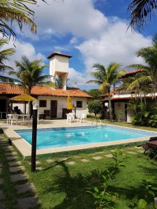 una piscina frente a una casa con palmeras en Búzios Canto da Cacau, en Búzios