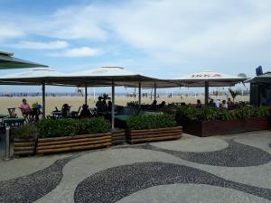 un patio con mesas y sombrillas en la playa en Copacabana Flat, en Río de Janeiro