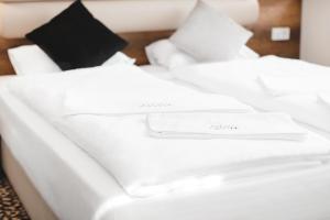 ein weißes Bett mit weißer Bettwäsche und Kissen darauf in der Unterkunft Hotel Castle Rastatt in Rastatt