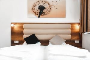 - un lit avec des draps blancs et une tête de lit en bois dans l'établissement Hotel Castle Rastatt, à Rastatt