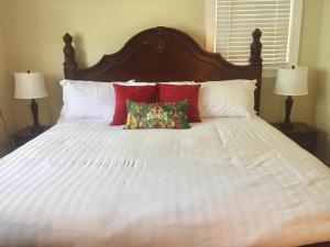 ein großes weißes Bett mit roten Kissen darauf in der Unterkunft Villa Riberia in St. Augustine