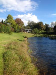 une rivière avec une maison en arrière-plan et un champ dans l'établissement Lakehouse Studio, à Kerikeri