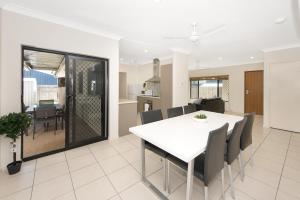 a dining room and kitchen with a white table and chairs at 3 bedroom central home in Townsville