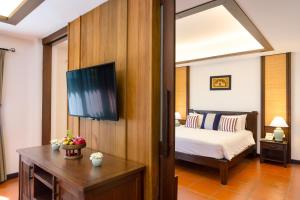 
a hotel room with a bed, desk and a television at Rimping Village in Chiang Mai
