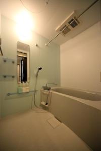 uma casa de banho com banheira e uma luz na parede em EX Itoman Apartment 602 em Itoman