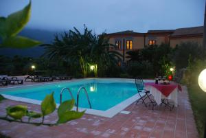 una piscina por la noche con mesa y sillas en Casale Romano Resort e Relais, en Motta Camastra