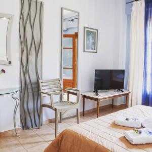 a bedroom with a bed and a chair and a television at Kastalia in Ammouliani