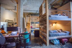 a room with two bunk beds and a desk and a table at PodShare Hollywood in Los Angeles