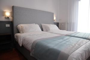 a large bed with white sheets and pillows at Dimora dell'Arte - Foresteria lombarda Smart Rent in Sesto San Giovanni