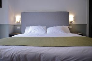 una camera da letto con un grande letto con lenzuola e cuscini bianchi di Dimora dell'Arte - Foresteria lombarda Smart Rent a Sesto San Giovanni