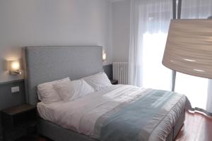 un letto in una camera da letto con una grande finestra di Dimora dell'Arte - Foresteria lombarda Smart Rent a Sesto San Giovanni