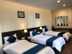a hotel room with three beds and a mirror at Kaveri Inn in Kathmandu