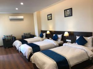 a row of four beds in a hotel room at Kaveri Inn in Kathmandu