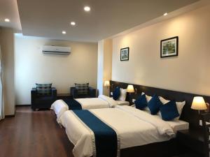 two beds in a hotel room with blue pillows at Kaveri Inn in Kathmandu