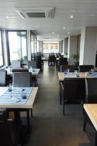 un comedor con mesas, sillas y ventanas en Les Fregates, en Veulettes-sur-Mer