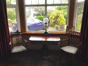 a desk in a room with two chairs and a window at Ramadale B&B in Stornoway