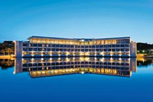 um edifício sobre a água à noite em Hotel Club Le Plein Sud Vacances Bleues em Hyères