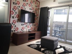 a living room with a flat screen tv on the wall at Cyro Apartments at Central Park in Durban