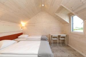 two beds in a small room with a window at Pina House in Rewal