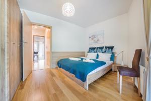 a bedroom with a blue bed and a chair at Apartamenty Sun & Snow Leśne Zacisze in Świnoujście
