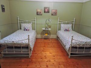 two beds in a room with wooden floors at Delightful Cottage in Queenscliff