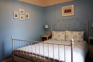 a bedroom with a bed with blue walls at Delightful Cottage in Queenscliff
