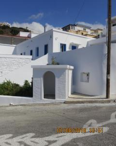 a white building with a door on the side of a street at Andoni's House in Pitrofós