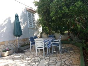 een tafel en stoelen en een parasol op een patio bij Apartman Nona in Povljana