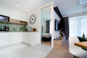 a kitchen and living room with a clock on the wall at LEMIR Apartments Wawrzyńca 21 in Kraków