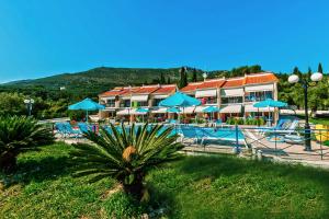 a resort with a swimming pool and blue umbrellas at Villa Diamond in Parga