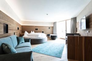 a living room with a couch and a bed at Aktiv- und Wellnesshotel Traube- Post in Curon Venosta