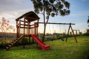 un parque infantil con tobogán y columpio en De Old Drift Guest Farm en Addo
