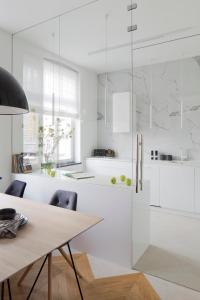 cocina blanca con mesa de madera y sillas en Apartament Sorello - Katowice Centrum, en Katowice