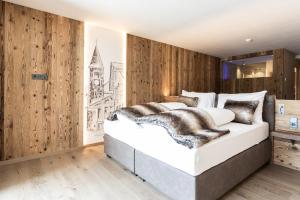 een slaapkamer met een groot wit bed en houten wanden bij Aktiv- und Wellnesshotel Traube- Post in Curon Venosta